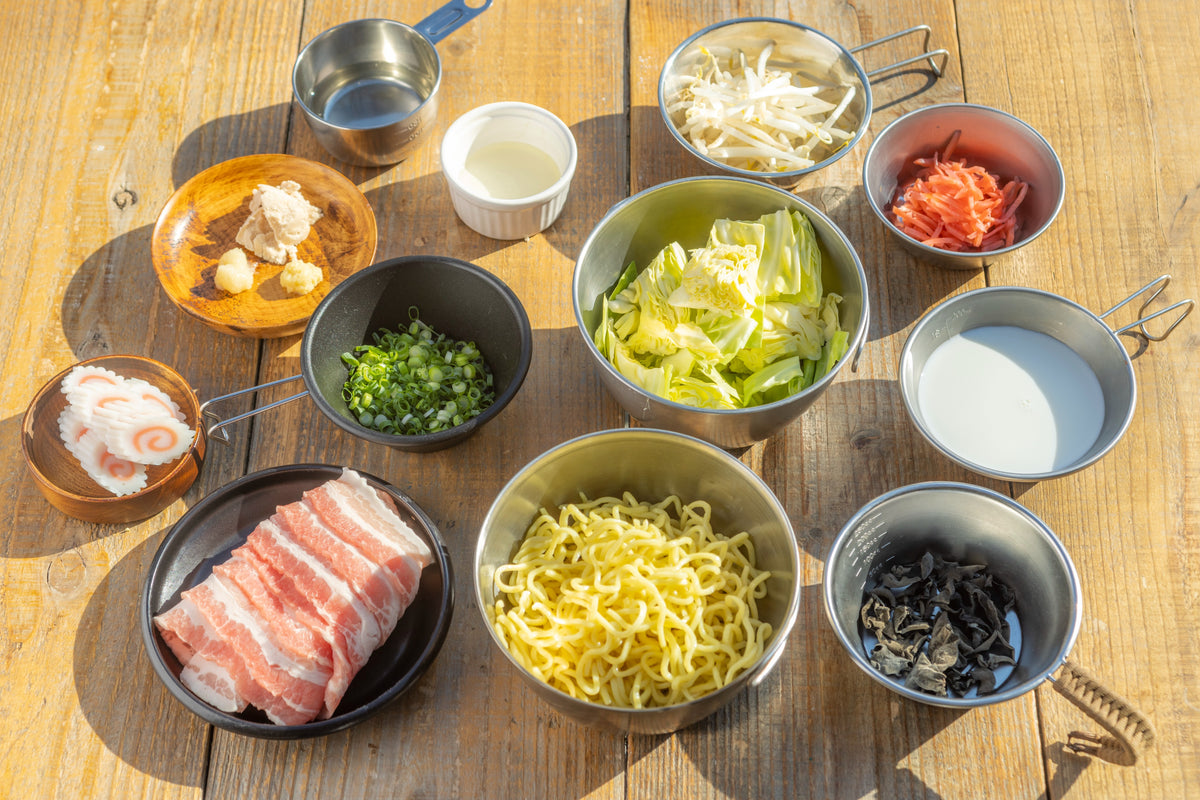 ラーメンの材料を並べた画像。中華麺、豚バラ肉、キャベツ、もやし、キクラゲなどが写っている