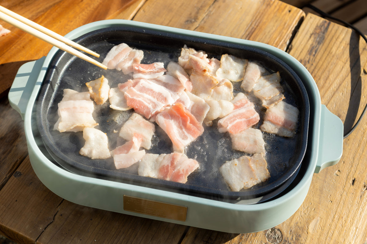 ホットプレートで豚バラ肉を炒めている様子を示す画像