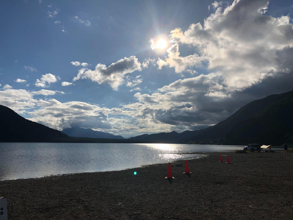 西湖湖畔キャンプ場から見た富士山と湖の風景。湖辺にキャンプサイトがある様子。